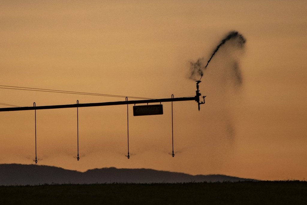 Irrigation equipment silhouetted against a field at dusk